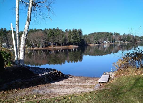 A lake with trees and a blue sky

Description automatically generated